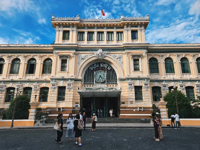 The ornate facade of Saigon Central Post Office beneath a blue sky